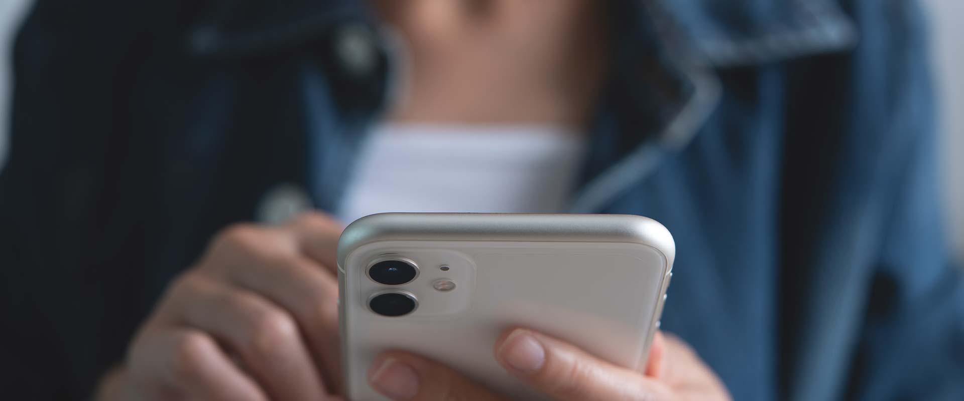 Sharenting, eine Frau hält ein Smartphone in ihren Händen und schaut sich Fotos ihrer Kinder an